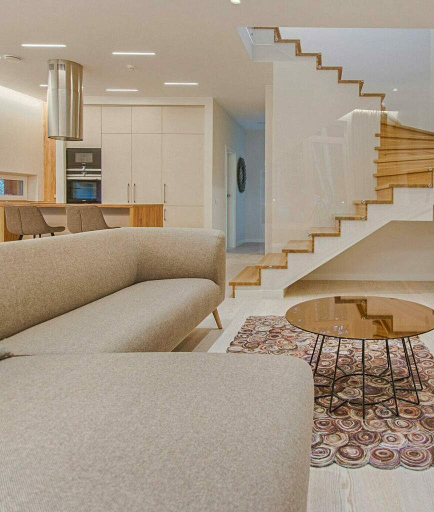 Spacious modern living room featuring stairs, a TV, and sleek furniture design.